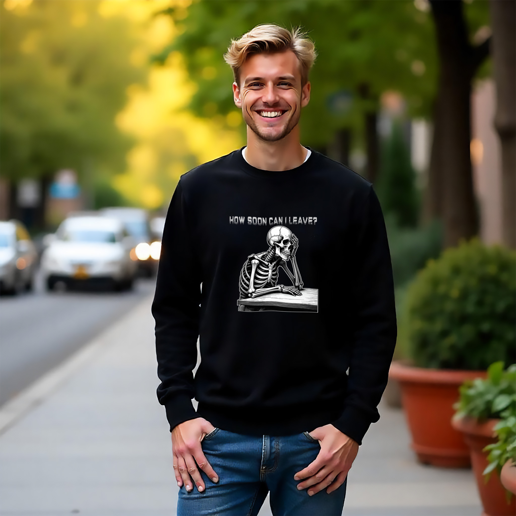 Man wearing a black sweatshirt with a bored skeleton at a desk "How soon can I leave?" in white text.